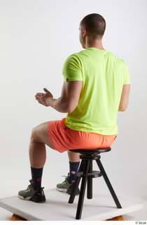 Joel  1 dressed green sneakers orange shorts sitting sports…